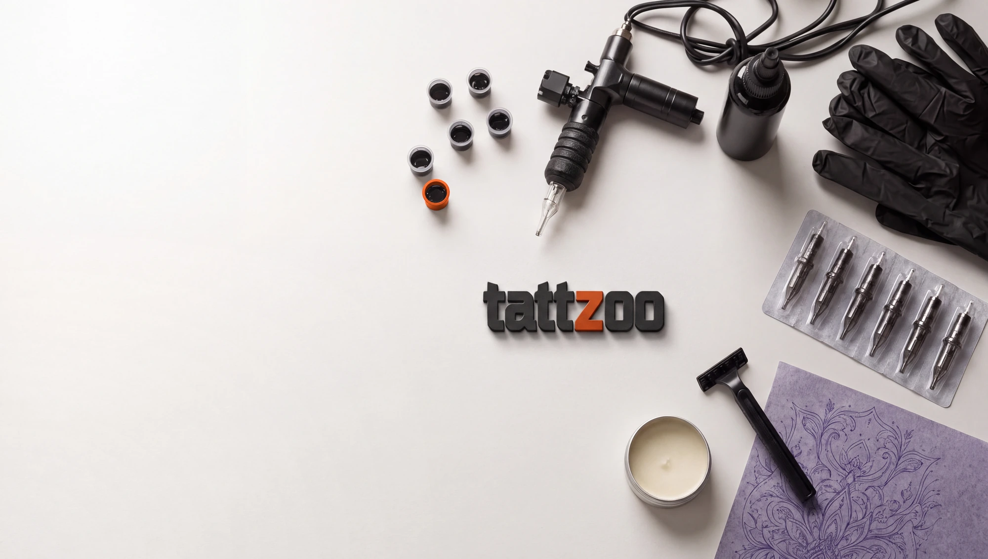 Die Auslage eines Studios von oben: Maschine, Farbkappen in Kupfer, Tinte, Folie und Handschuhe, dazwischen der Schriftzug tattzoo als Objekt